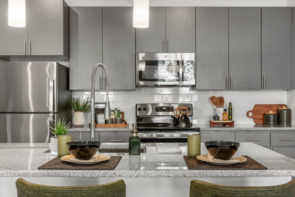 A modern kitchen with a stainless steel refrigerator and a center island with two bowls on top.