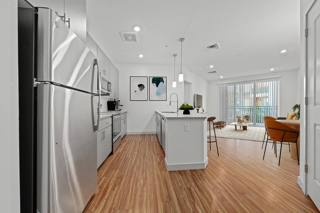 A modern kitchen with wooden floors and stainless steel appliances.