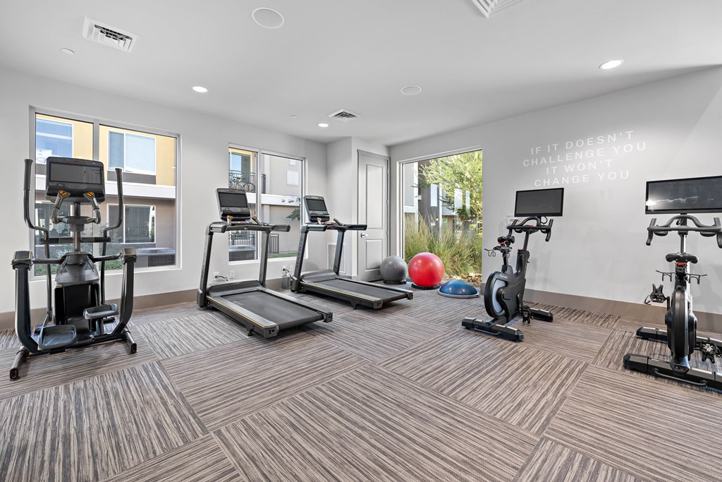 A gym with a variety of equipment including treadmills, stationary bikes, and weight machines.