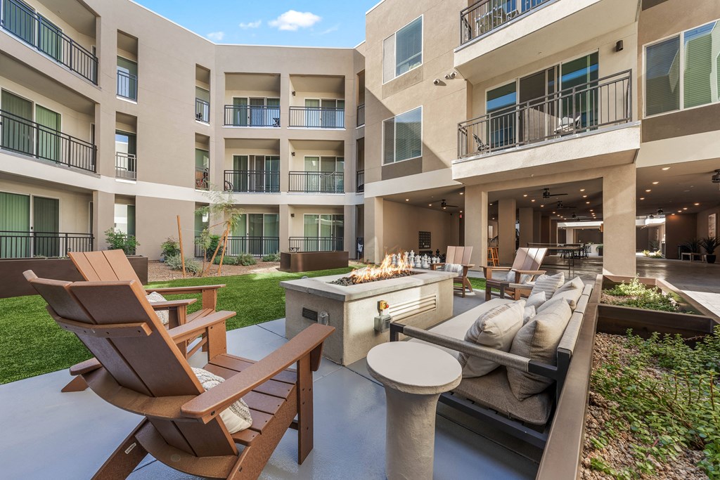 A patio area with a table, chairs and a grill.