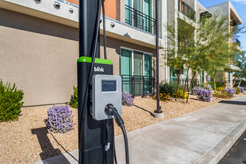 A Blink charging station is installed on a sidewalk in front of a building.