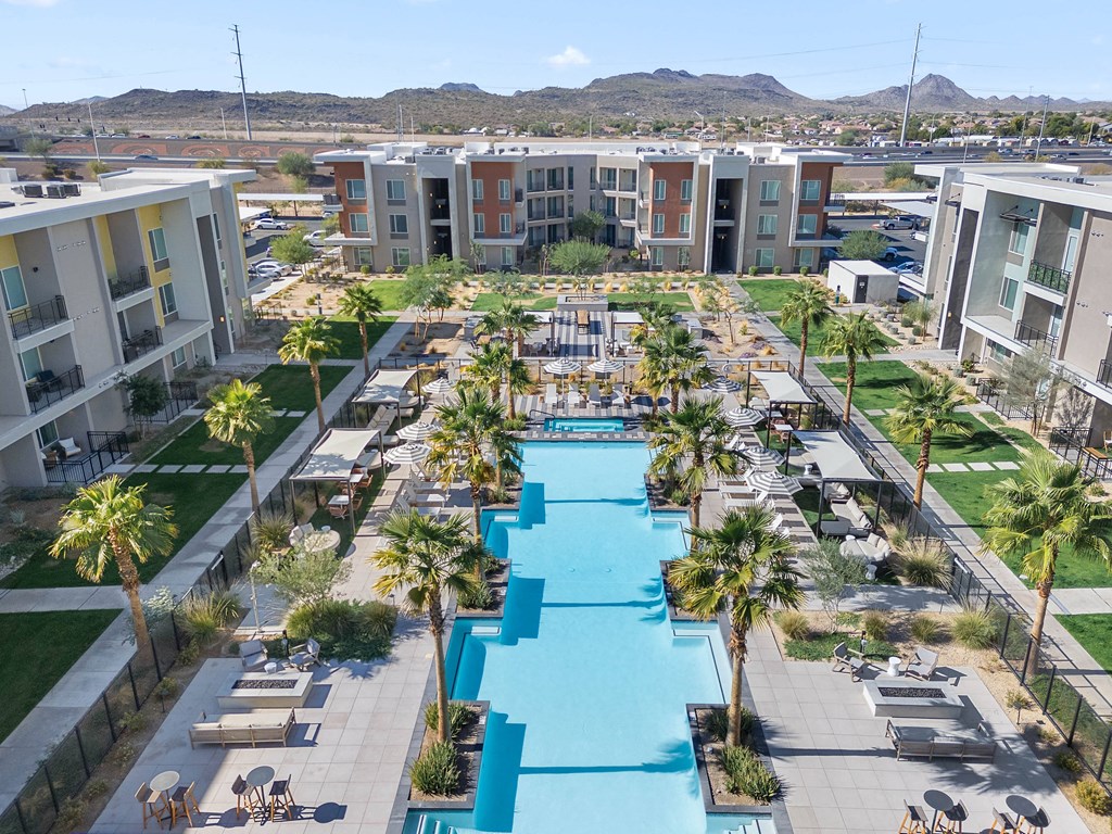 A large swimming pool surrounded by palm trees and lounge chairs in a residential area.