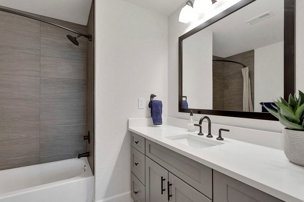 A modern bathroom with a white countertop and a large mirror.