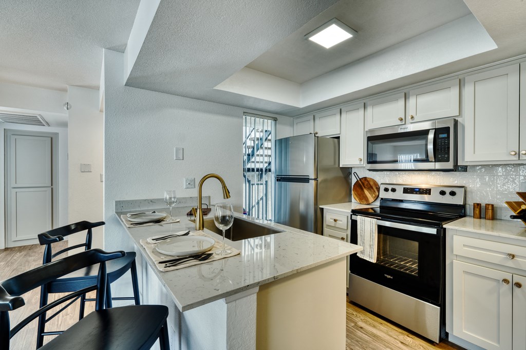 an open kitchen with a marble counter top and a sink