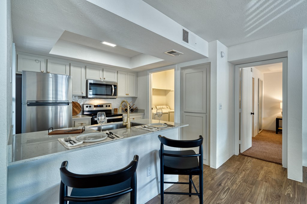 a kitchen with a bar and two chairs in front of a