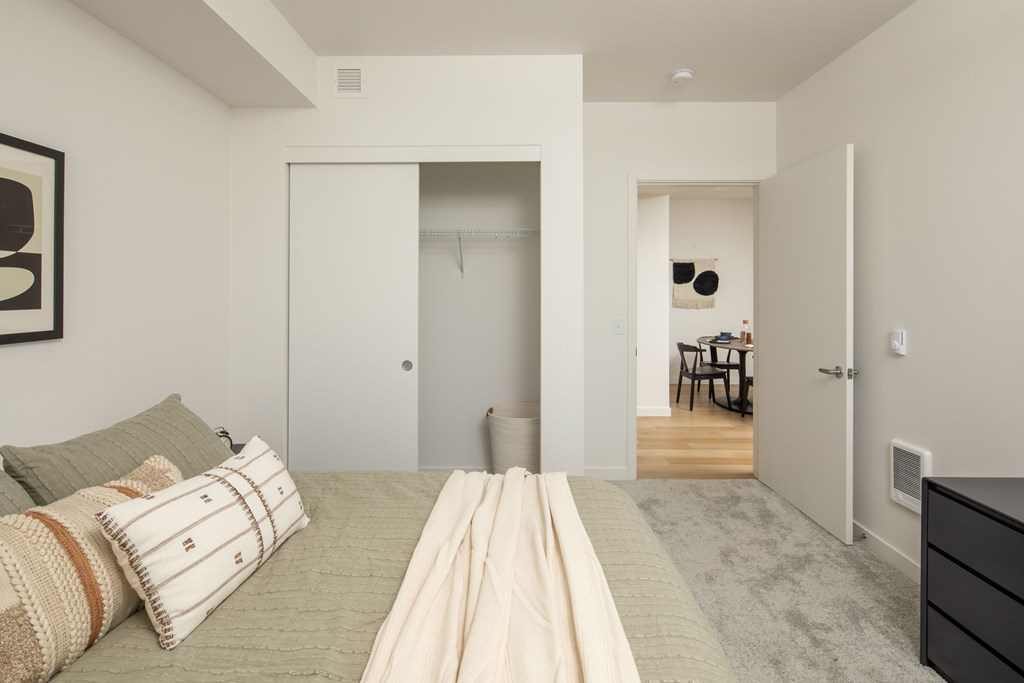 A bedroom with a bed, a chair, and a wardrobe.