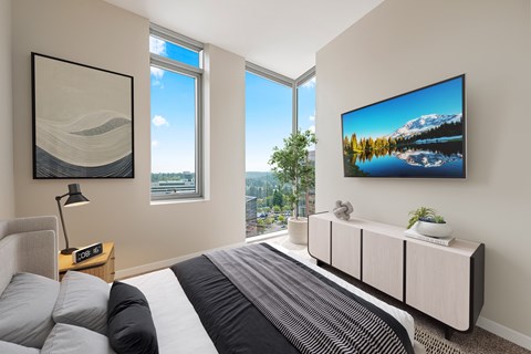 A bedroom with a large bed and a TV mounted on the wall.