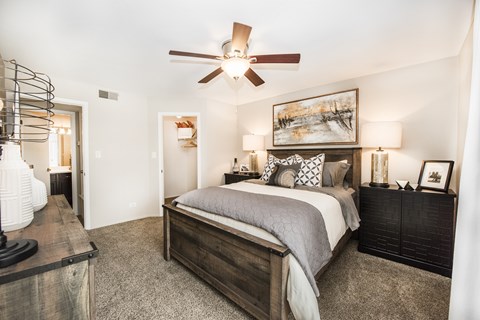 A bedroom with a large bed and a ceiling fan.