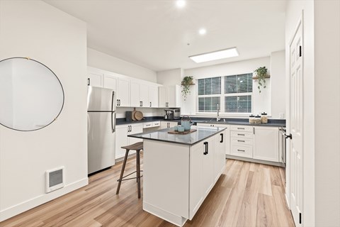 A modern kitchen with white cabinets and a wooden floor.