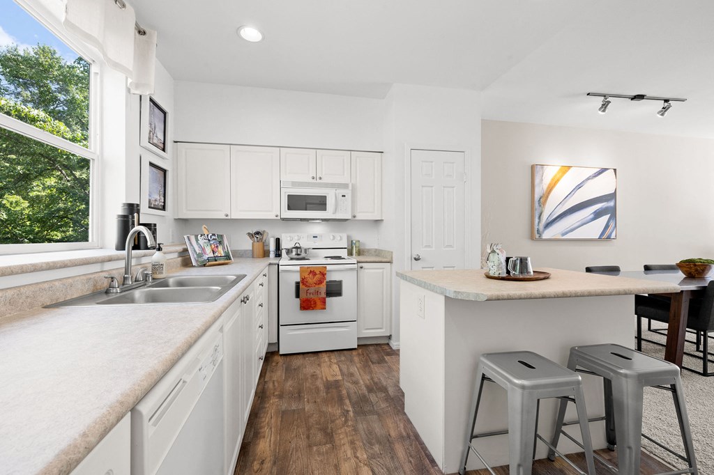 a kitchen with white cabinets and a large window