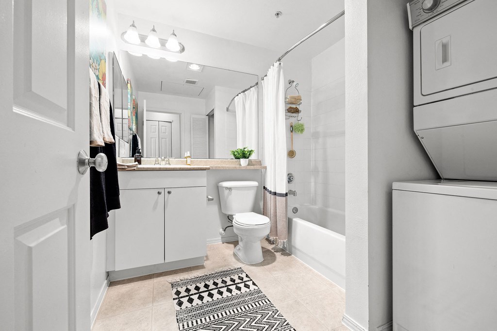 a small bathroom with a white washer and dryer next to a toilet