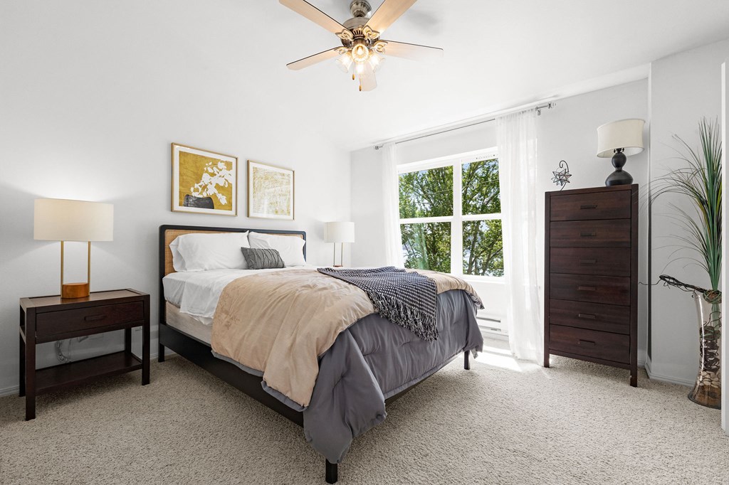 a bedroom with a large window and a ceiling fan