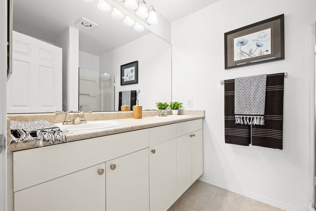 a bathroom with white cabinets and a large mirror
