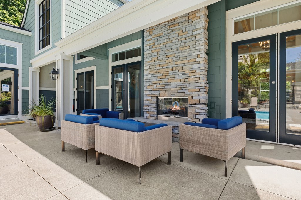 a patio with couches and a fireplace in front of a building