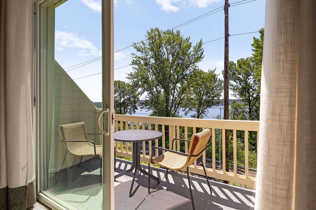 a balcony with a table and two chairs and a view of the water