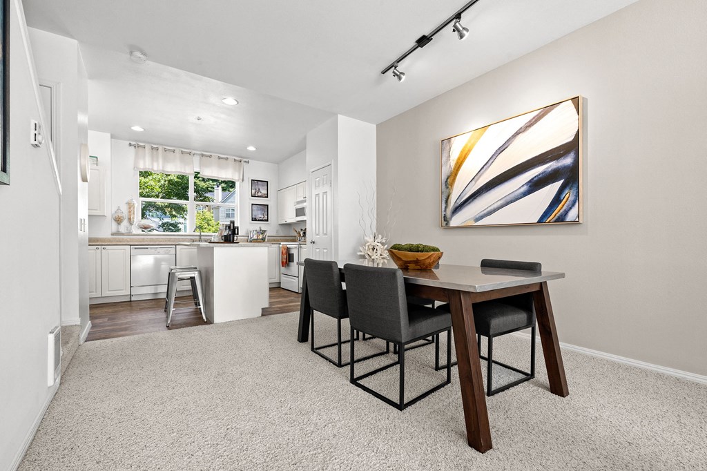 a dining area with a table and chairs and a kitchen in the background