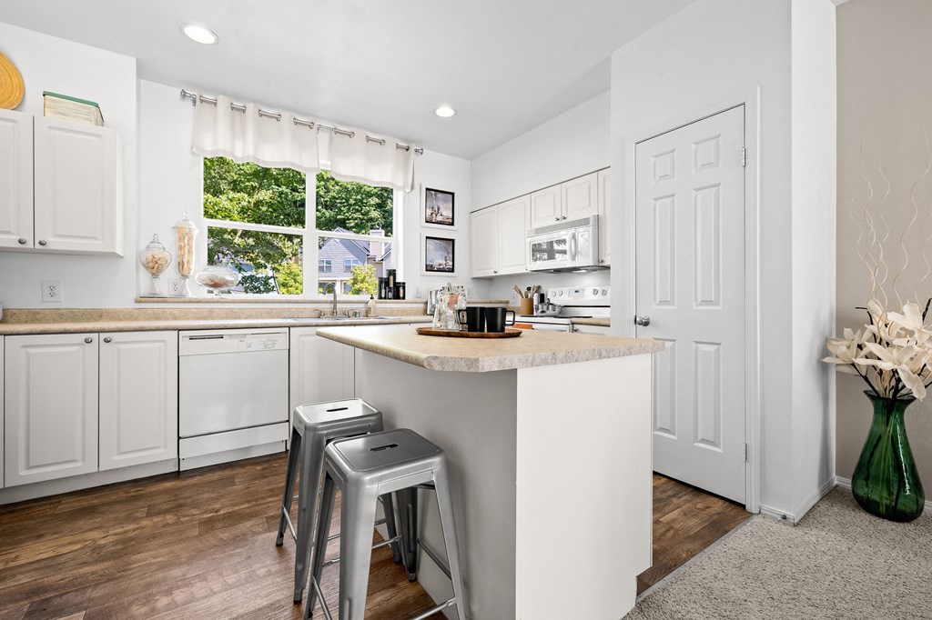 a kitchen with white cabinets and a white island with two stools