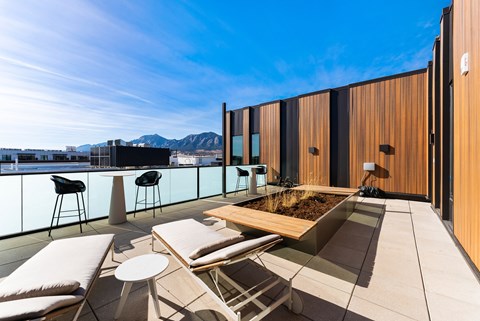 a rooftop terrace with tables and chairs and a view of the mountains