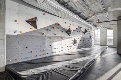 a climbing wall in a building with a large tarp on the ground