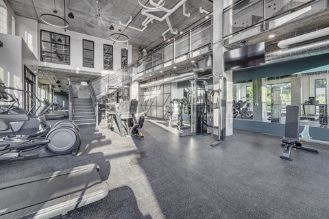 a gym floor with cardio equipment and a staircase