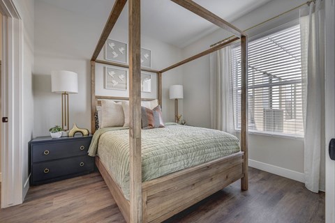 a bedroom with a four poster bed and a large window