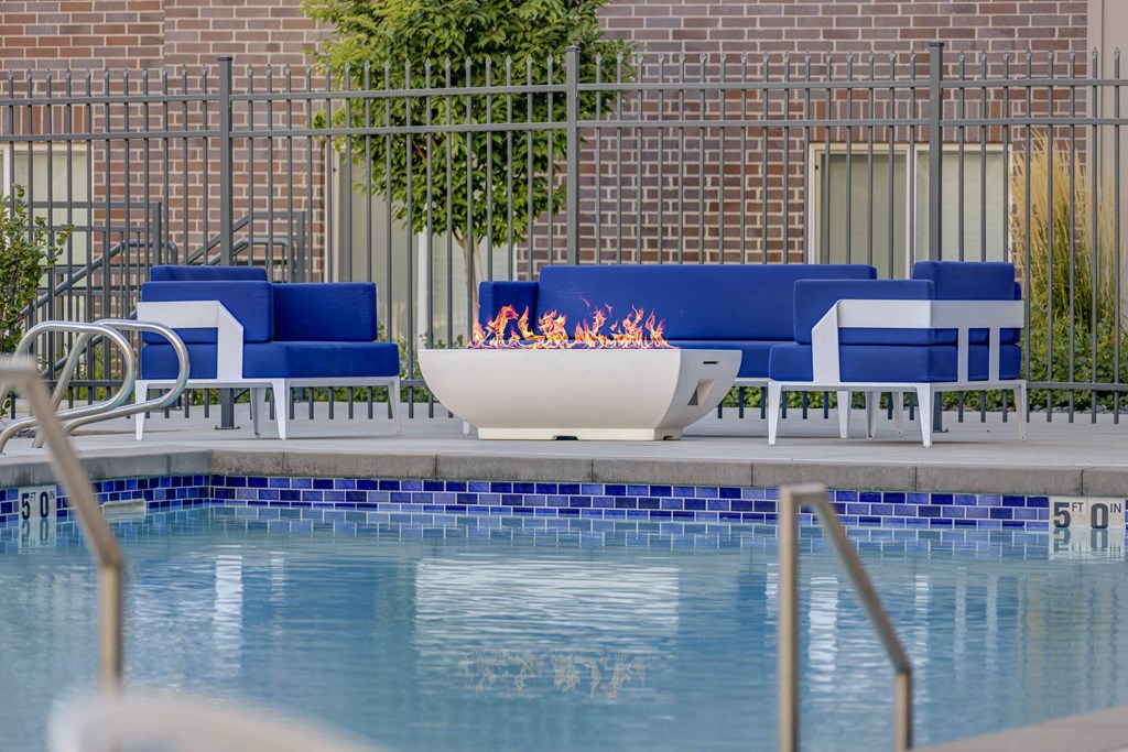 a fire pit in the middle of a pool with blue chairs around it