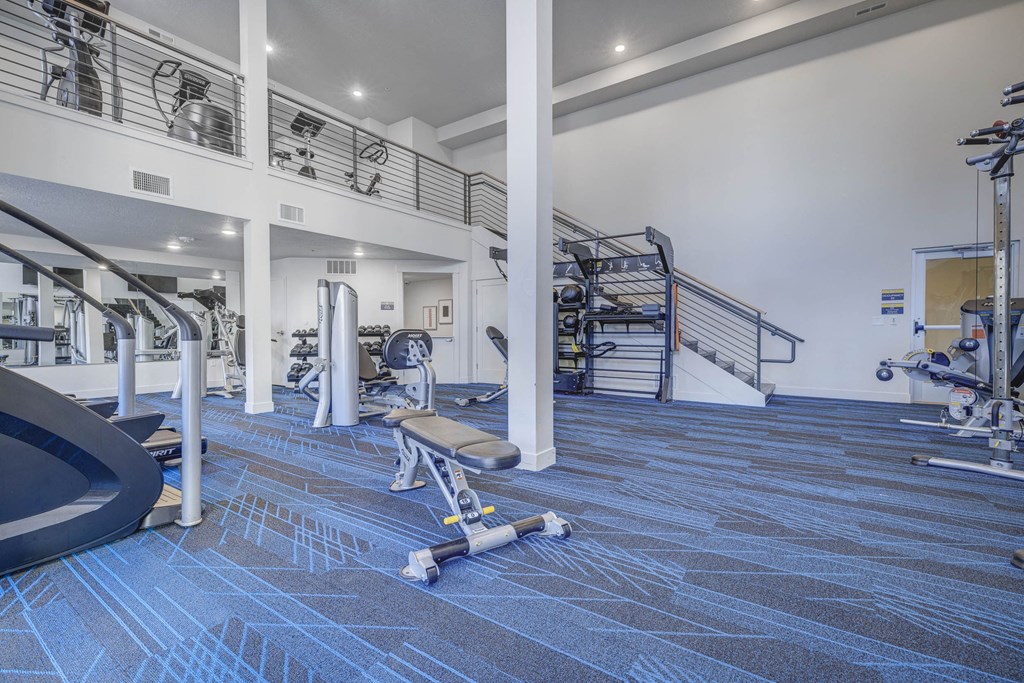 a gym with weights and cardio equipment and a spiral staircase