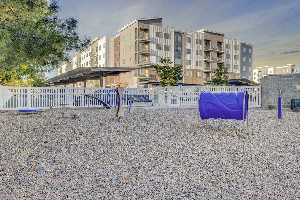 a playground with a blue slide and swing set in front of an apartment building