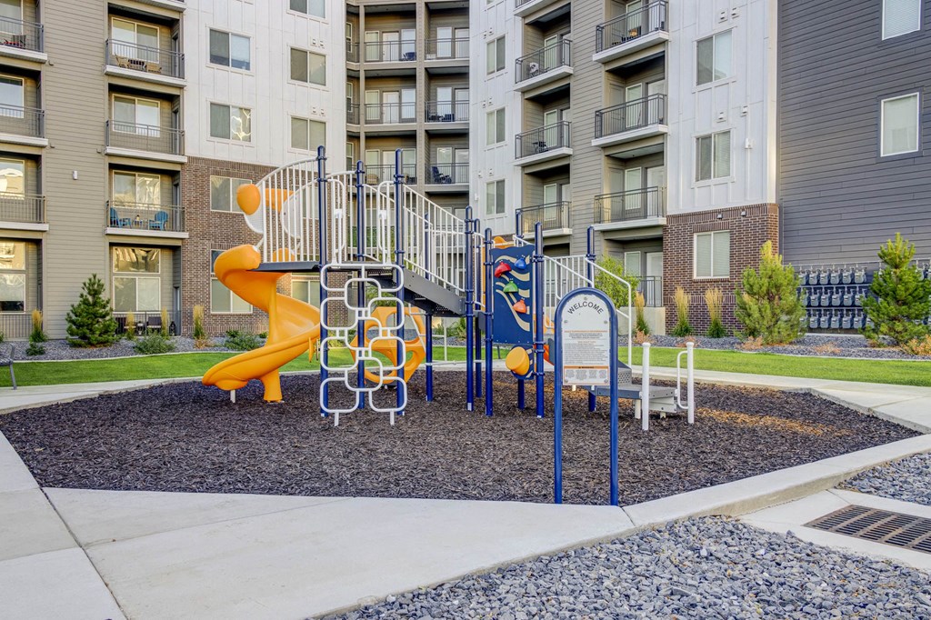 a playground with a slide in front of an apartment building