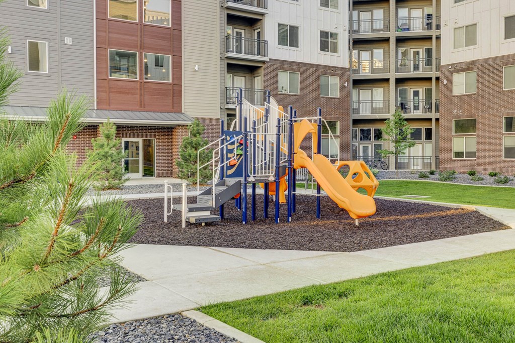 a playground in front of an apartment building with a yellow slide