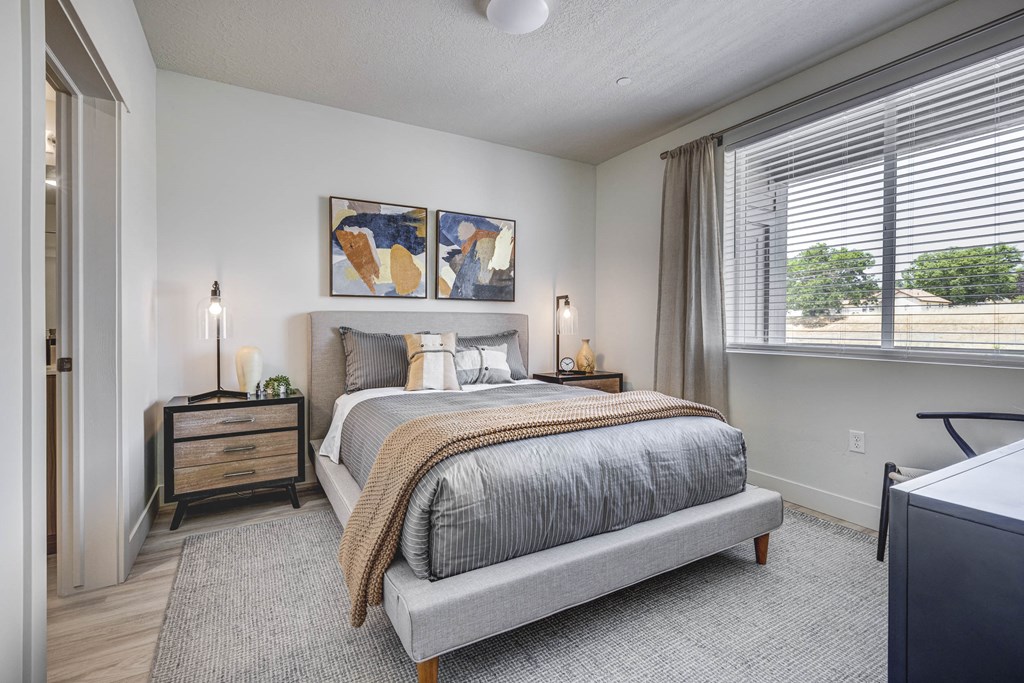 Angled shot of bedroom showing large window, and decorated bed