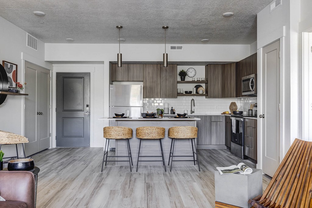 Shot of kitchen and front door, wood tone floors, and designed furnishings
