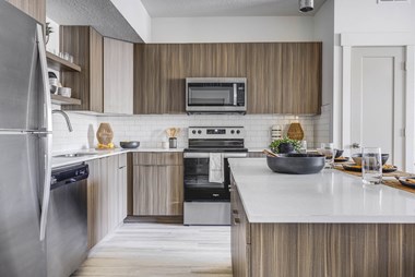 Kitchen with wood cabinetry, island countertop,  and stainless steel appliances