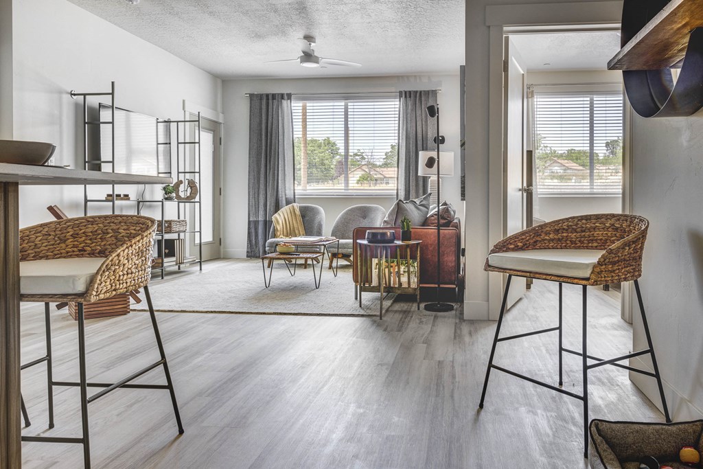 Shot of apartment living room with wood tone floors, designed furnishings, and large windows