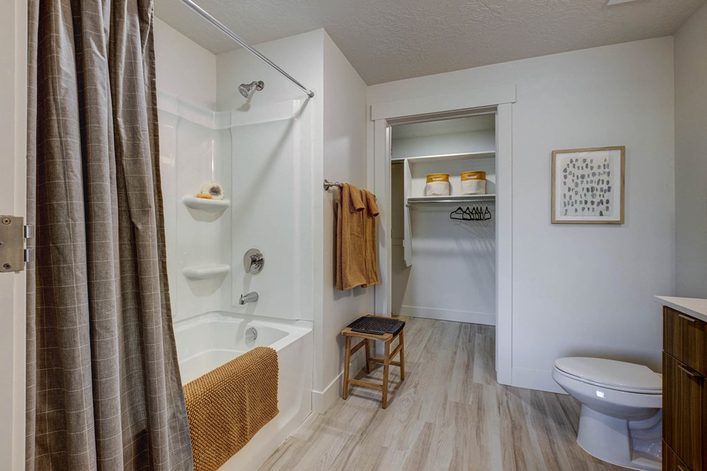Bathroom with tan décor accents, tub, and storage closet
