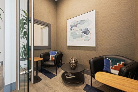 a living room with black furniture and a painting on the wall