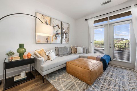 a living room with a couch and a chair and two windows
