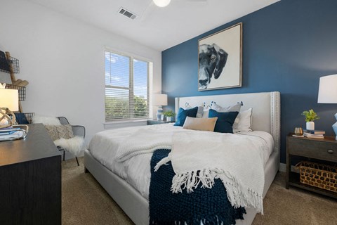 bedroom with blue accent wall and white bed with white blanket and pillows