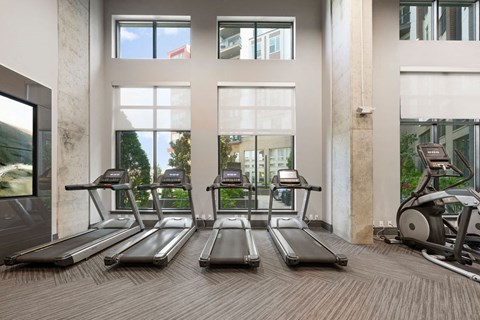 a gym with cardio equipment and windows in a building