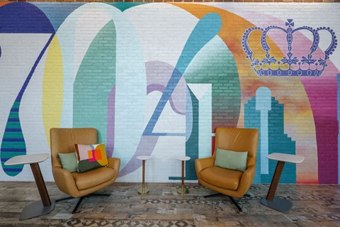 two leather chairs in front of a wall with a rainbow mural