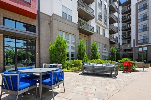 a patio with tables and chairs in front of an apartment building