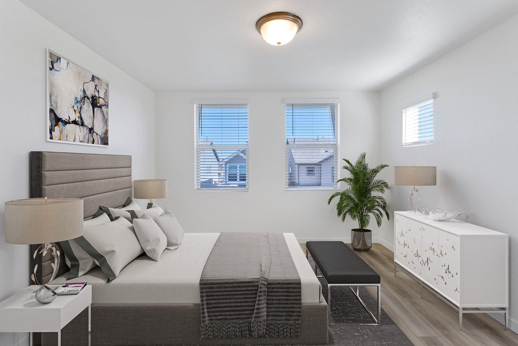 a bedroom with a bed and a dresser and two windows