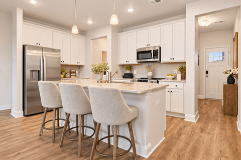 A kitchen with white cabinets and a marble countertop.