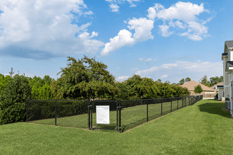 A sign is posted on a fence in a grassy area.