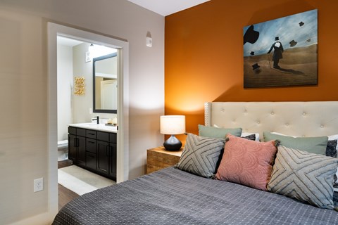 A bedroom with a bed, nightstand, and a painting on the wall.