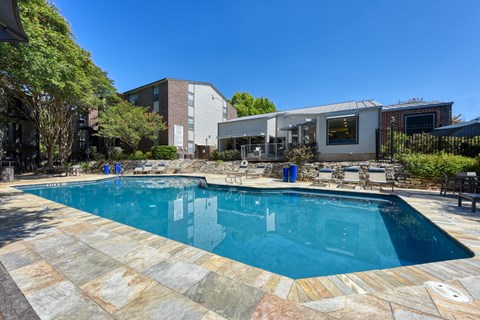 a swimming pool with lounge chairs and a house in the background