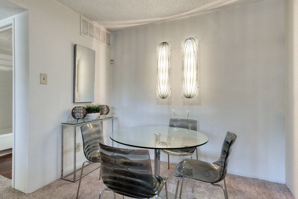 a dining room with a glass table and four chairs