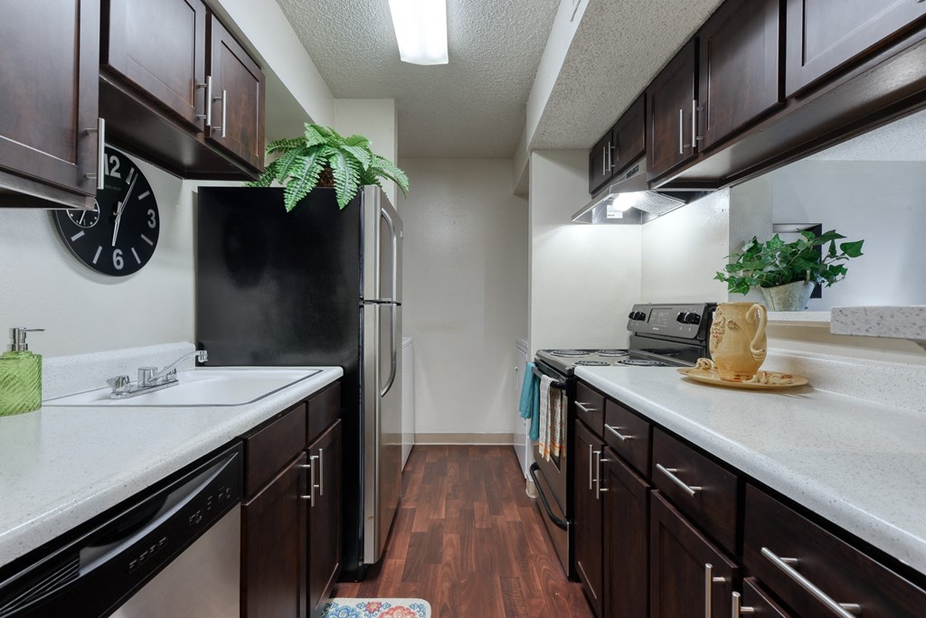 a kitchen with dark wood cabinets and white countertops