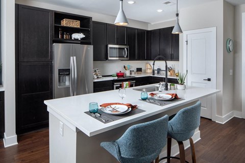 A kitchen with a white island and black cabinets.