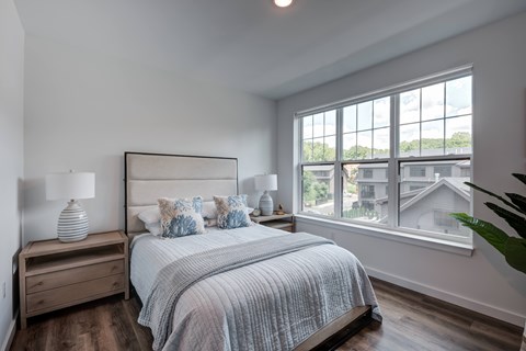 A bedroom with a large bed and a window overlooking a residential area.